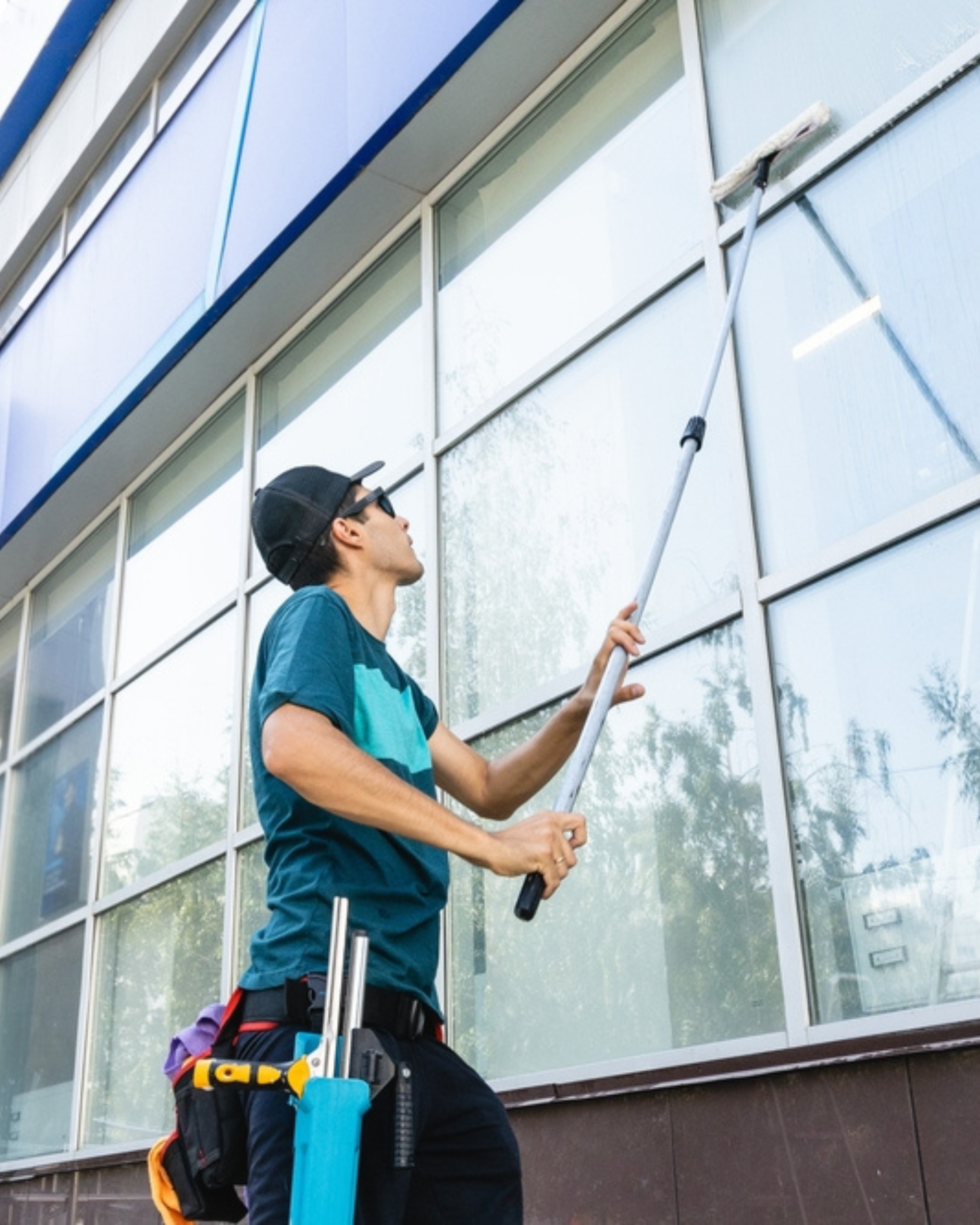 Mik Oy technician cleaning the exterior windows of a commercial office building using a professional water-fed pole in Espoo, Finland