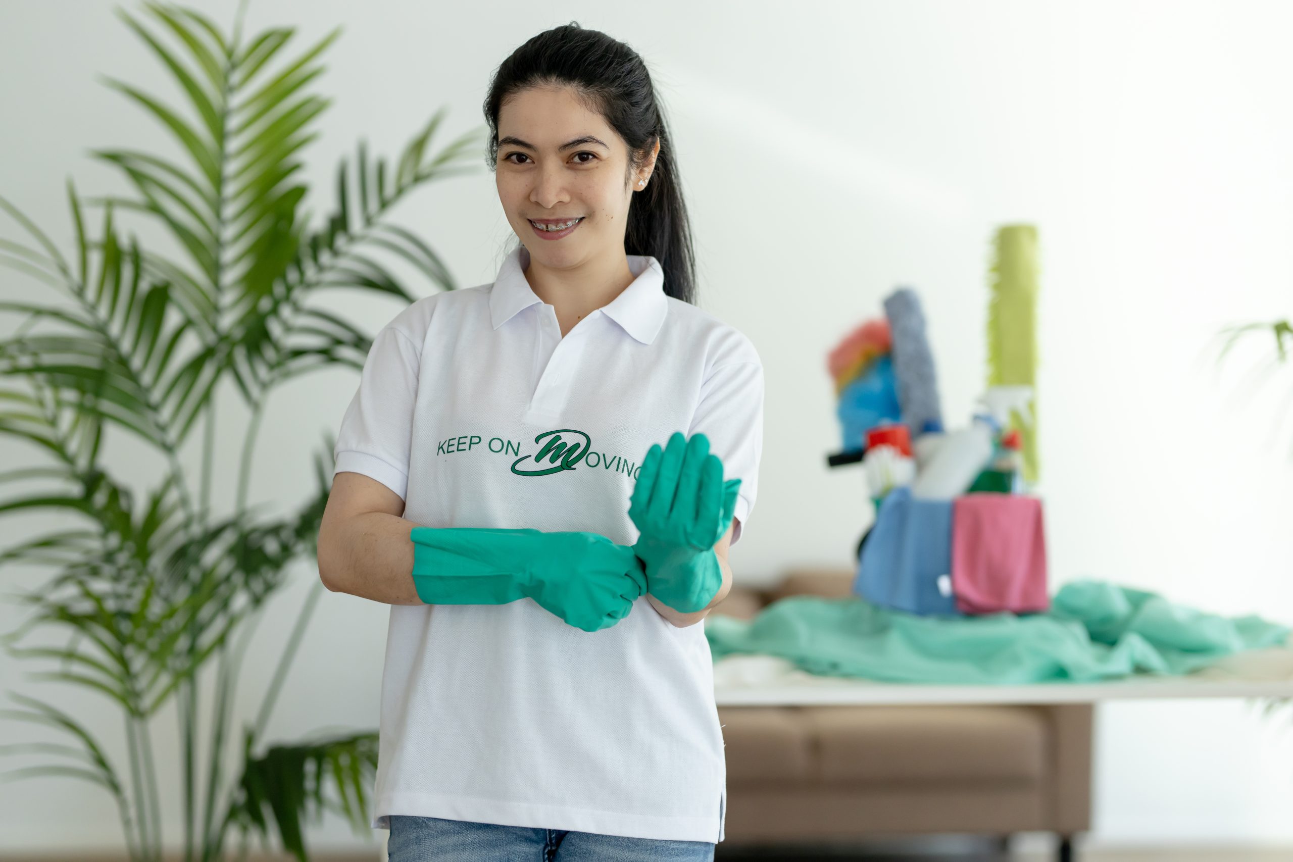 Friendly Mik Oy uniformed cleaner wearing green gloves and ready with professional cleaning supplies in the background, Helsinki, Finland