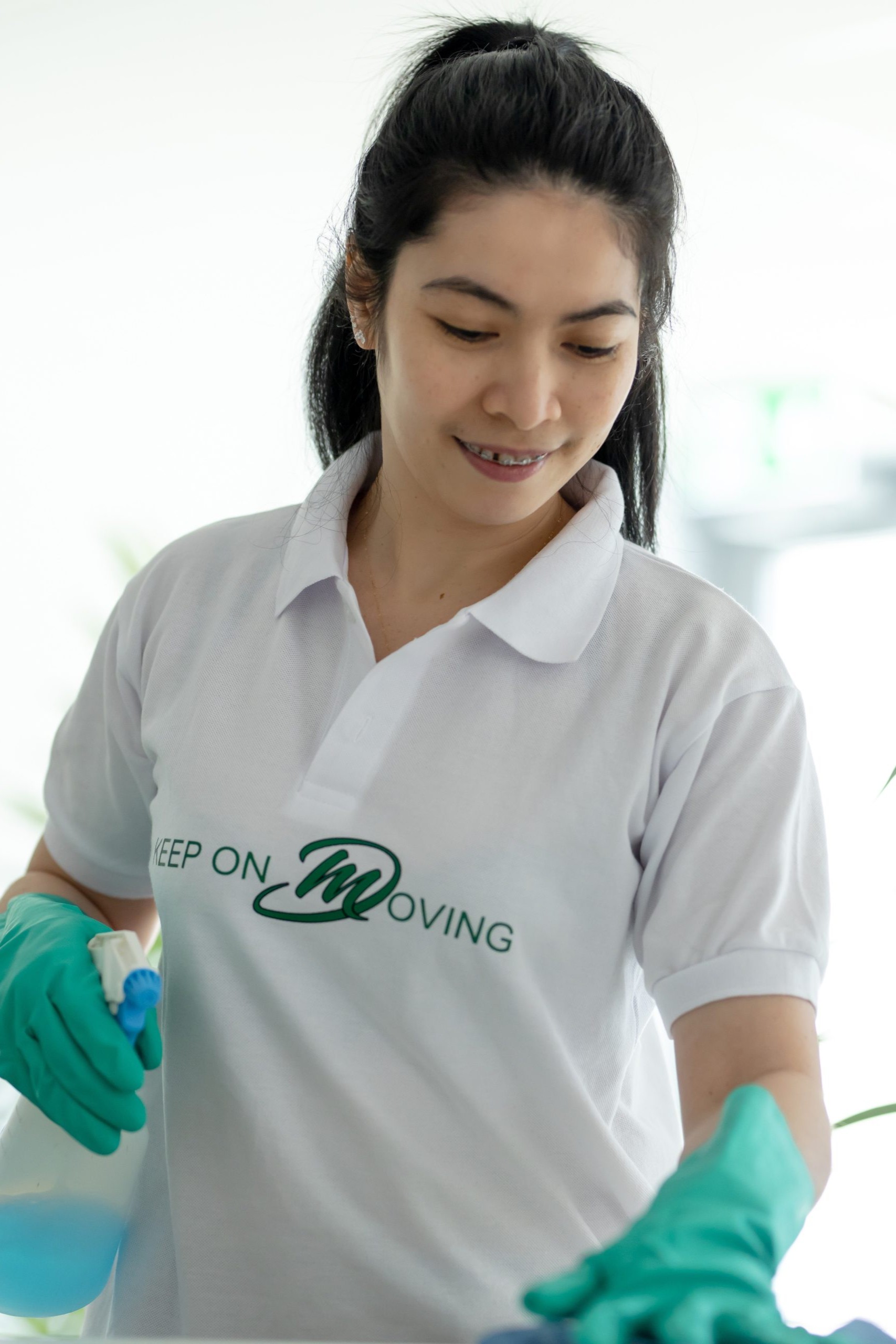 Mik Oy professional cleaner in green gloves spraying glass cleaner during an AirBnB bathroom turnover cleaning in Helsinki, Finland
