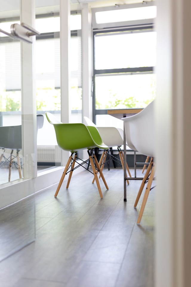 Clean modern office meeting room with green and white chairs, tidy floors, and natural light after Mik Oy professional office cleaning in Espoo, Finland