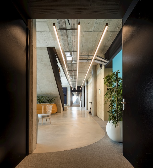Clean modern co-working office corridor with polished concrete floors, designer lighting, and tidy common areas maintained by Mik Oy in Helsinki, Finland
