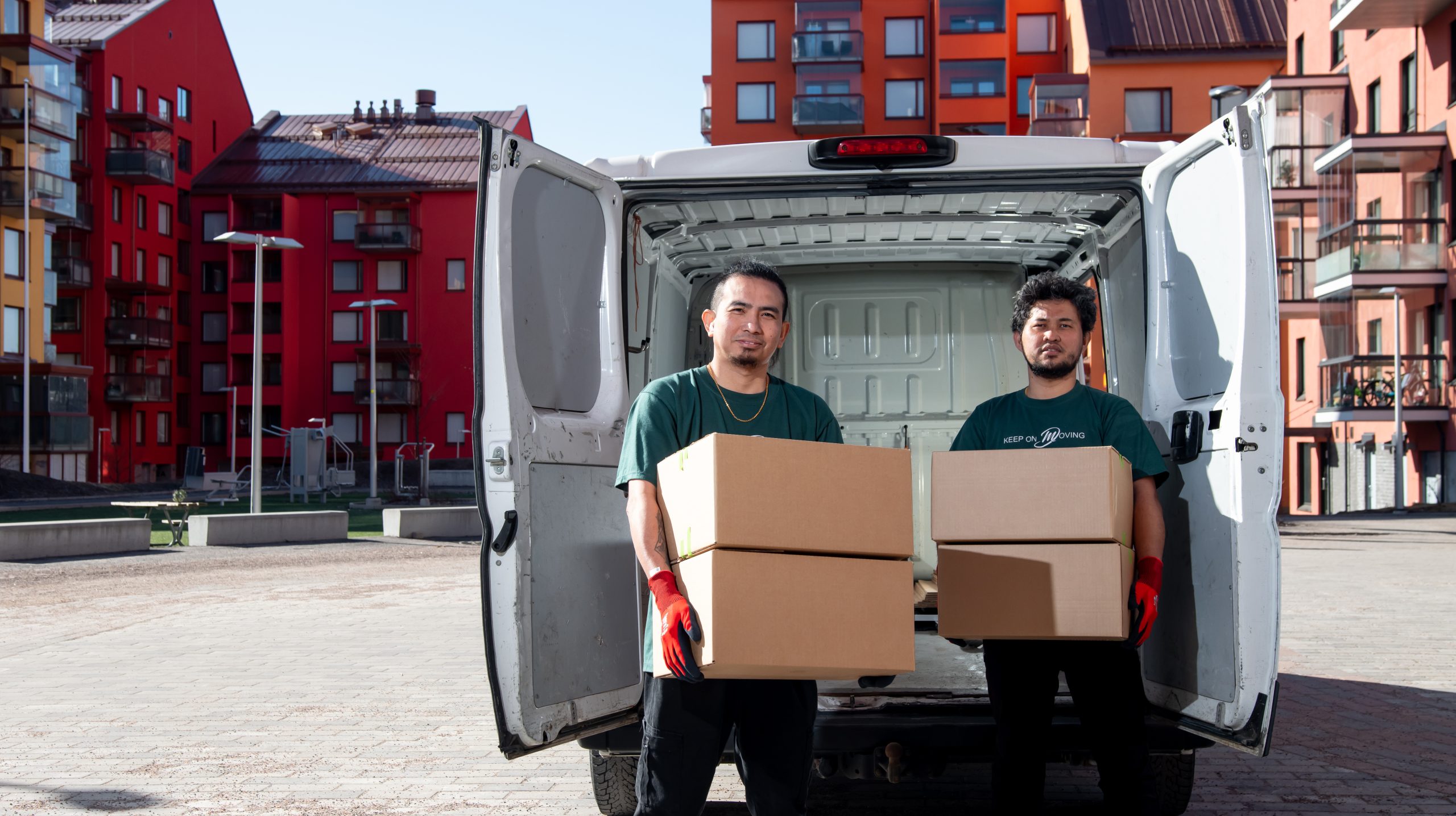 Kaksi Mik Oy:n työntekijää kantaa pahvilaatikoita pakettiautosta kerrostaloalueella Helsingissä
