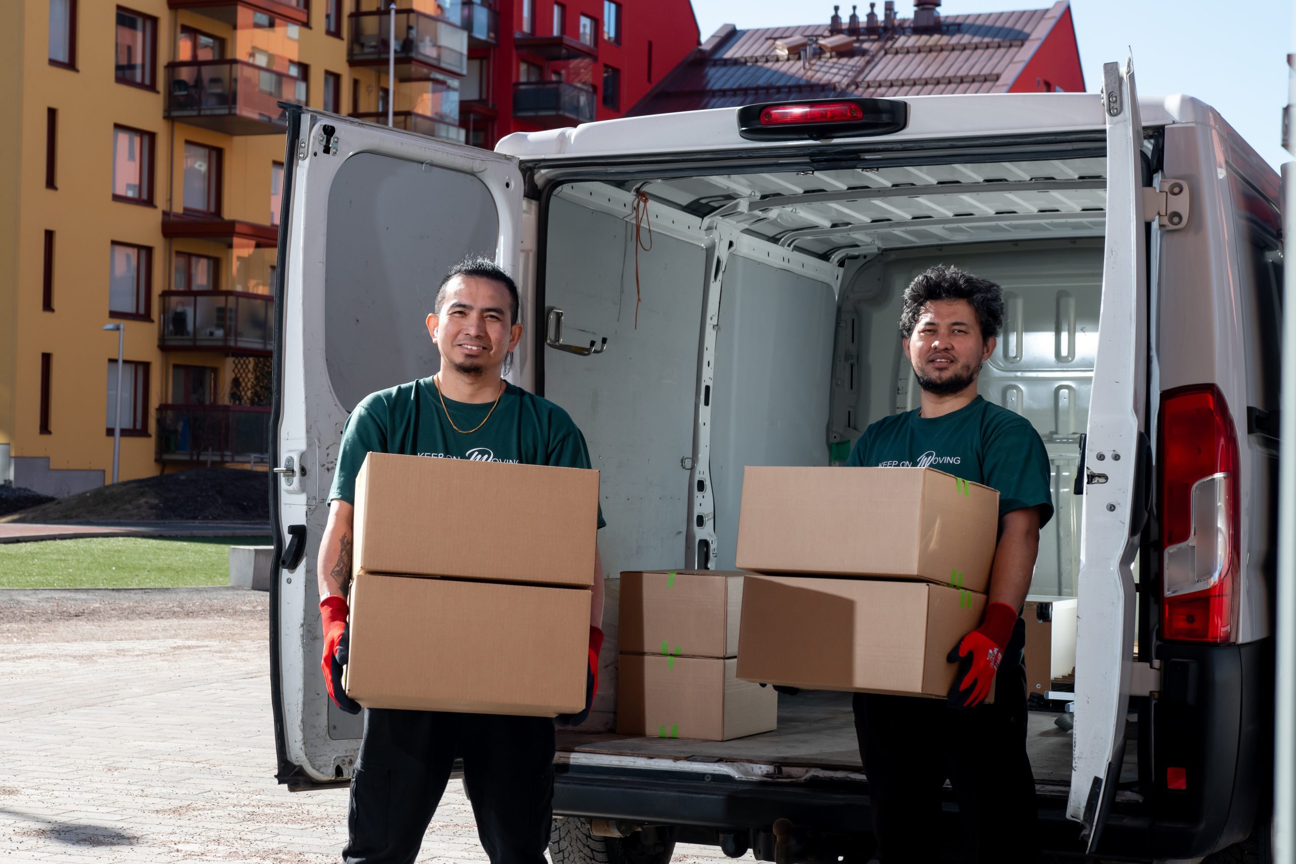 Mik Oy:n kotimuuttotiimi kantaa muuttolaatikoita pakettiautosta kerrostaloasunnon edessä Helsingissä