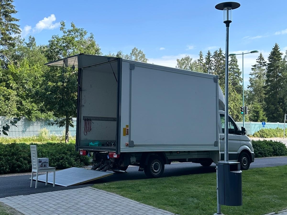 Mik Oy:n valkoinen kuorma-auto lastausalusta laskettuna toimitusta varten vihreässä kesämaisemassa Järvenpäässä